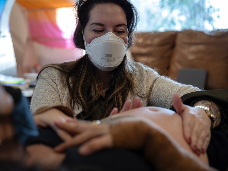 Midwife Madeleine Wisner evaluates Chloé Mick's belly during a maternal care consultation at Mick's home in Sacramento on Feb. 6, 2024. Photo by Miguel Gutierrez Jr., CalMatters