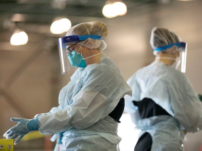 Nurses prepare to enter the testing area at a drive thru COVID-19 testing facility at Cal Expo in Sacramento on April 15, 2020. The nurses work in teams of four and take shifts throughout the day. Photo by Anne Wernikoff for CalMatters