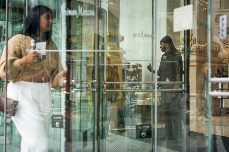 A security guard works the front entrance of a Neiman Marcus retail location in downtown San Francisco on April 15, 2024. Retail theft has plagued the area, and numerous storefronts sit vacant. Photo by Loren Elliott for CalMatters