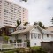 A high-rise apartment tower stands behind single-family homes near Wilshire Boulevard and 6th Street in Santa Monica on May 24, 2023. Photo by Zaydee Sanchez for CalMatters