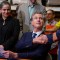 Flanked by state lawmakers, Gov. Gavin Newsom shakes another lawmakers hand in celebration while seated at a desk at a Home Depot in San Jose.