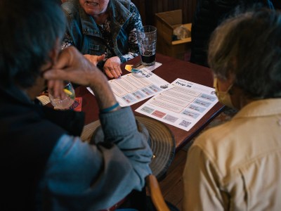 Three persons gather around a wooden table with flyers with information on ballot propositions.