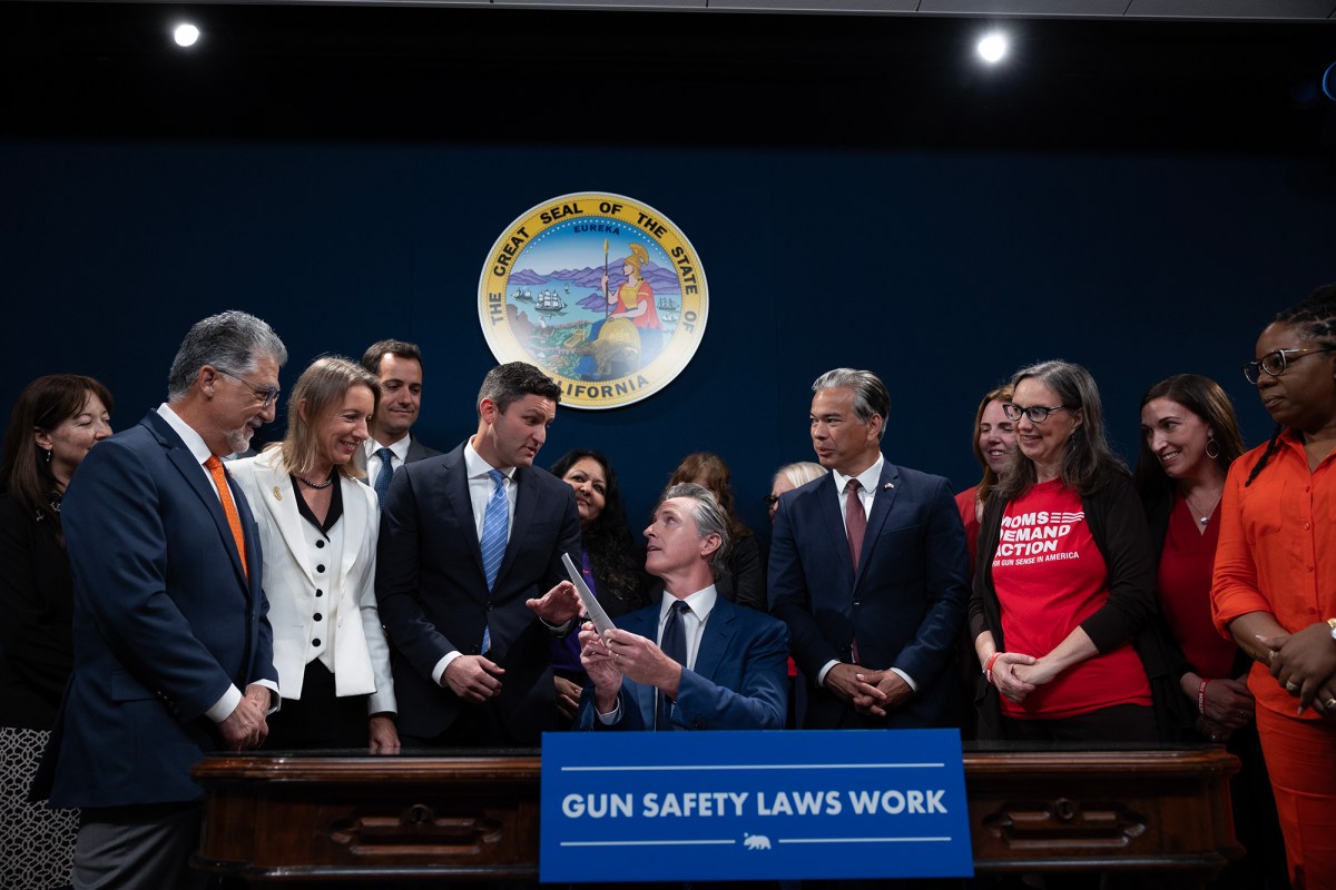 Flanked by lawmakers and gun safety advocates, Gov. Gavin Newsom signs new gun legislation into law at the Capitol annex in Sacramento on Sept. 26, 2023. Photo by Miguel Gutierrez Jr., CalMatters