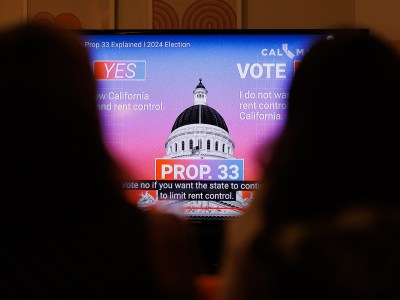 A view people looking at a monitor displaying a video with information on Prop. 33 at a voter information event.