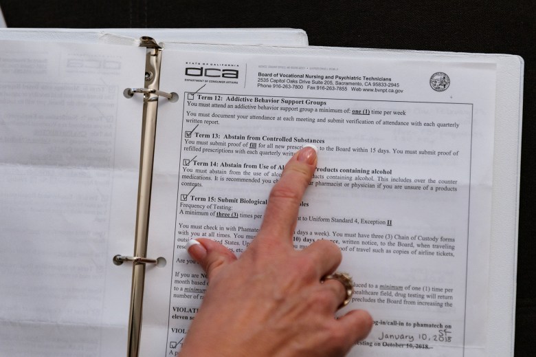 A close up photo of a hand pointing at text on a document in a binder. The text reads, "Term 13: Abstain from Controlled Substances". There is other related text on the document, related to addiction.