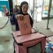 A person wearing a hijab and purple sweatshirt inserts a pink ballot into a pink ballot box at a polling place.