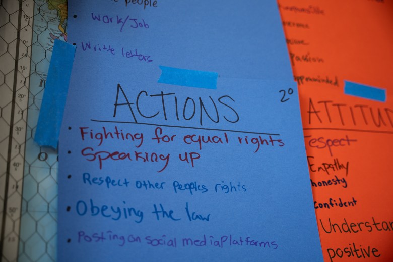 A close-up view of a poster hung up on a classroom wall that reads, "Actions: Fighting for equal rights, speaking up, respect other people's rights, obeying the law, posting on social media platforms."