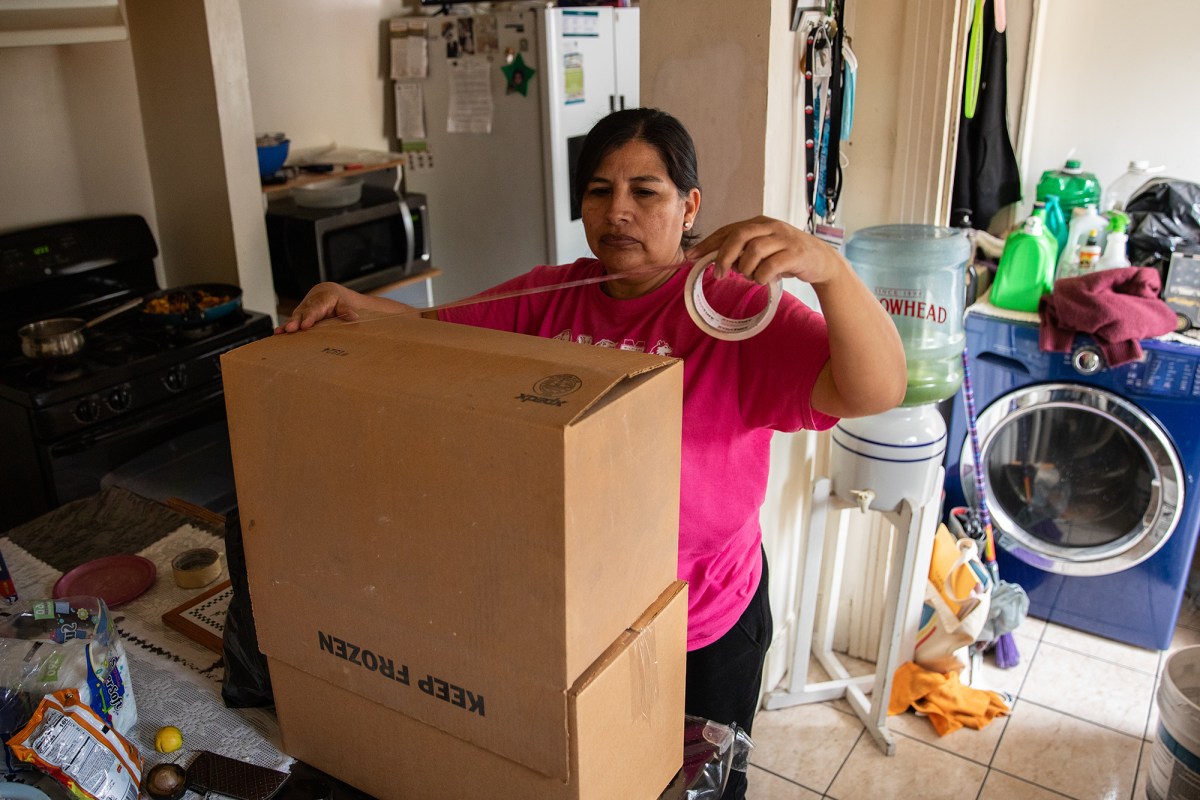 María Vela assembles a cardboard box as her family gets ready to move out of their home of nearly 30 years in East Los Angeles on Dec. 17, 2023. Photo by Adriana Heldiz, CalMatters